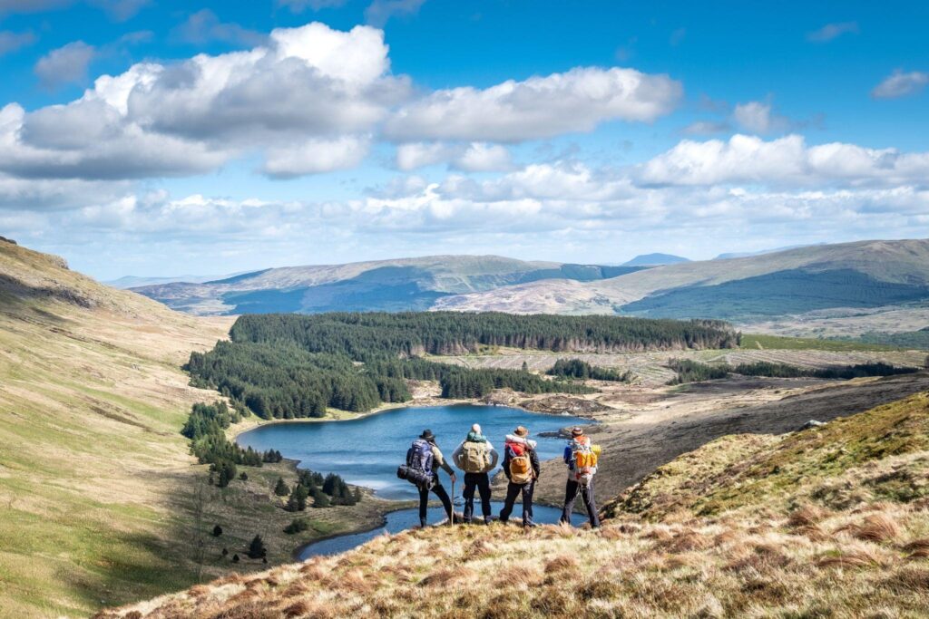 Walkers looking out over a reservoir and hills in rural Wales