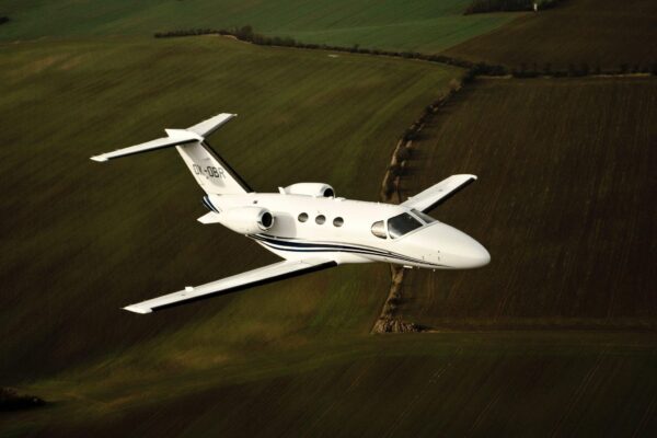 Private jet flying low over green fields in the UK