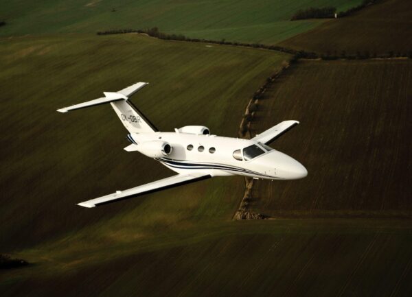 Private jet flying low over green fields in the UK